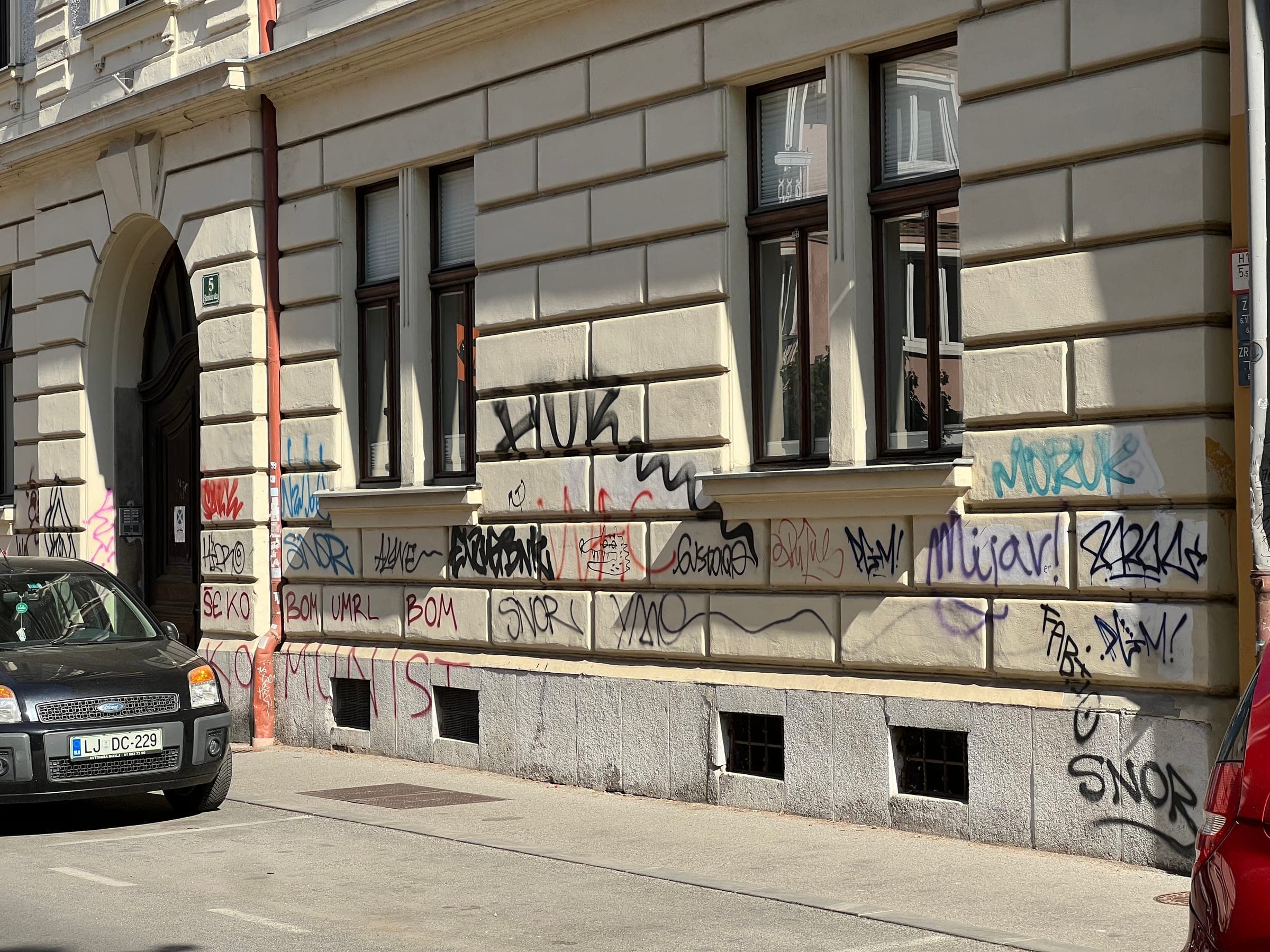 Podpisi SNOR, HUR in drugi grafiti prekrivajo pritlično fasado na Slomškovi ulici 5 v Ljubljani.