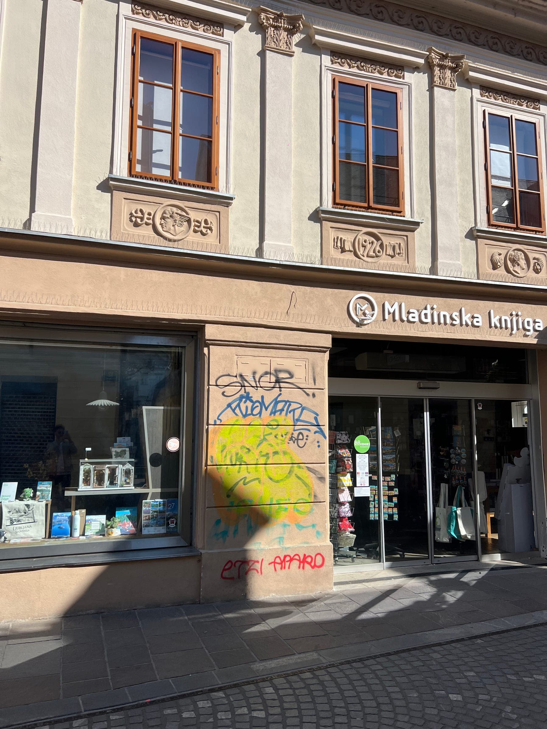 Podpis SNOR in drugi grafiti ob vhodu v knjigarno na Trubarjevi cesti 11.