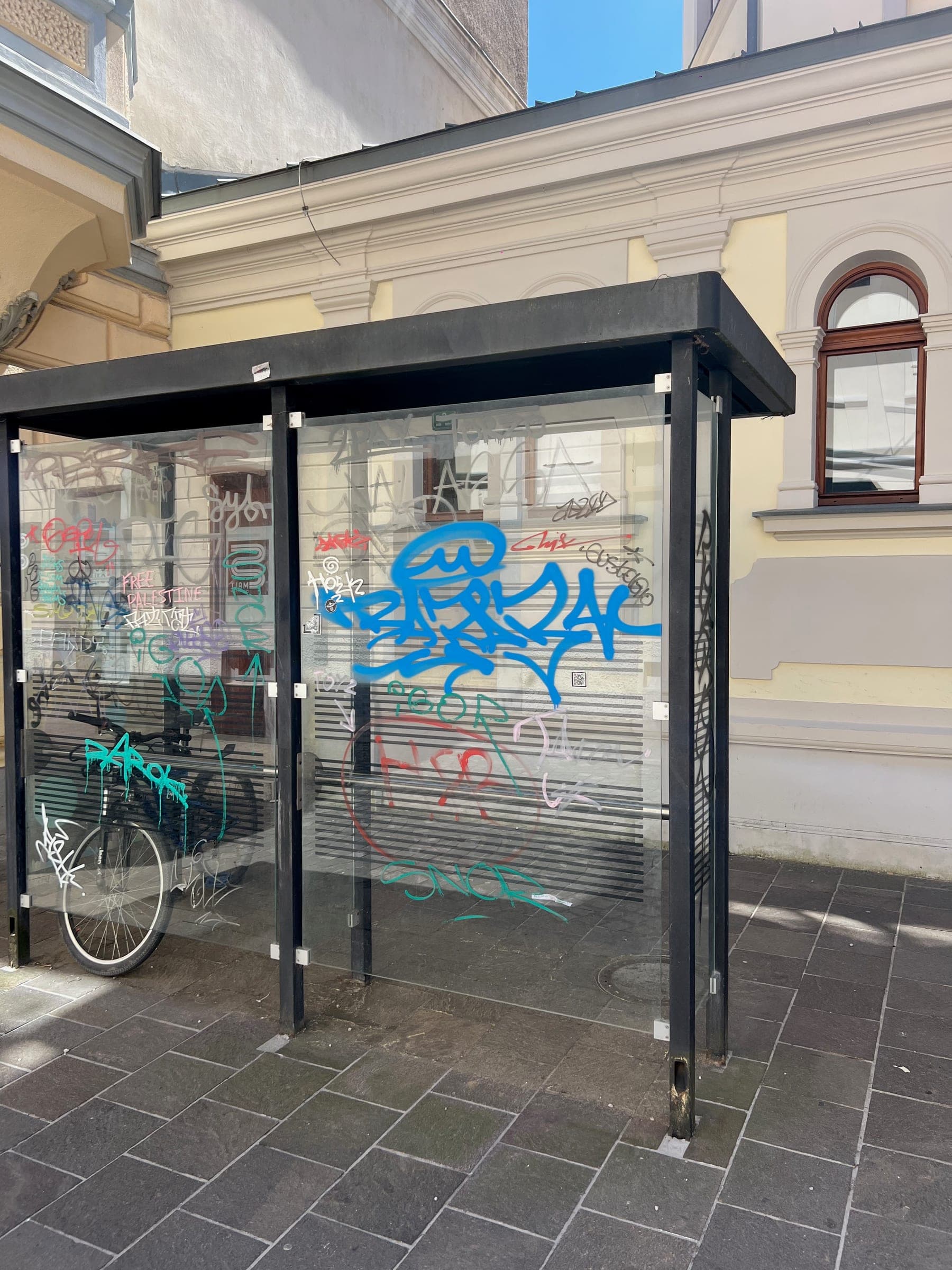 Podpis SNOR in drugi grafiti na steklu nadstrešnice na Prečni ulici 7.